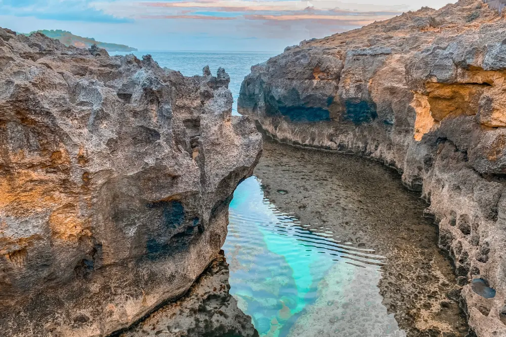 Scenic overview of Angel Billabong natural infinity pool in West Nusa Penida Tour with Axestone Fast Cruise, featuring crystal clear tidal pool surrounded by ancient rock formations.