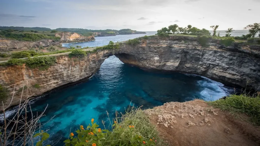 Dramatic coastal cliffs overlooking turquoise waters at Broken Beach with rugged limestone formations and natural bridge structure, best visited during West Nusa Penida Tour with Axe Stone Fast Cruise daily departures