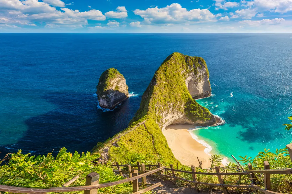 Steep wooden staircase descending to Kelingking Beach during a West Nusa Penida Tour, an adventurous hike accessible with Axestone Fast Cruise.